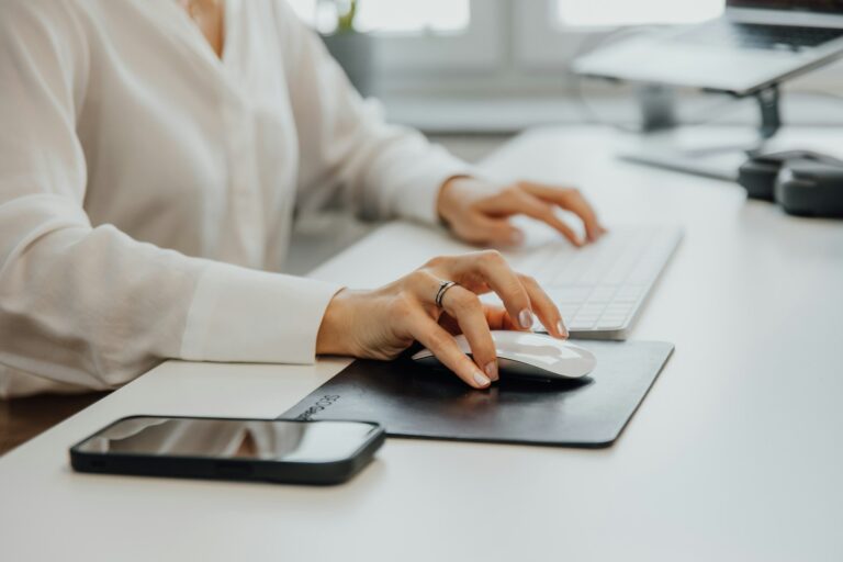 A Woman Sitting At A Desk Using A Computer Mouse