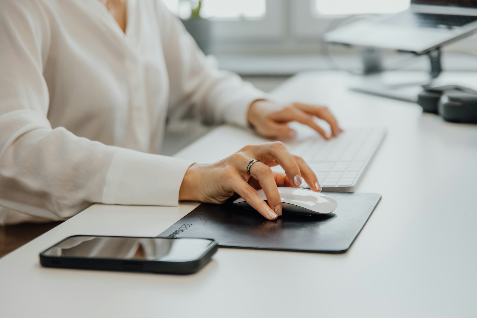 a woman sitting at a desk using a computer mouse